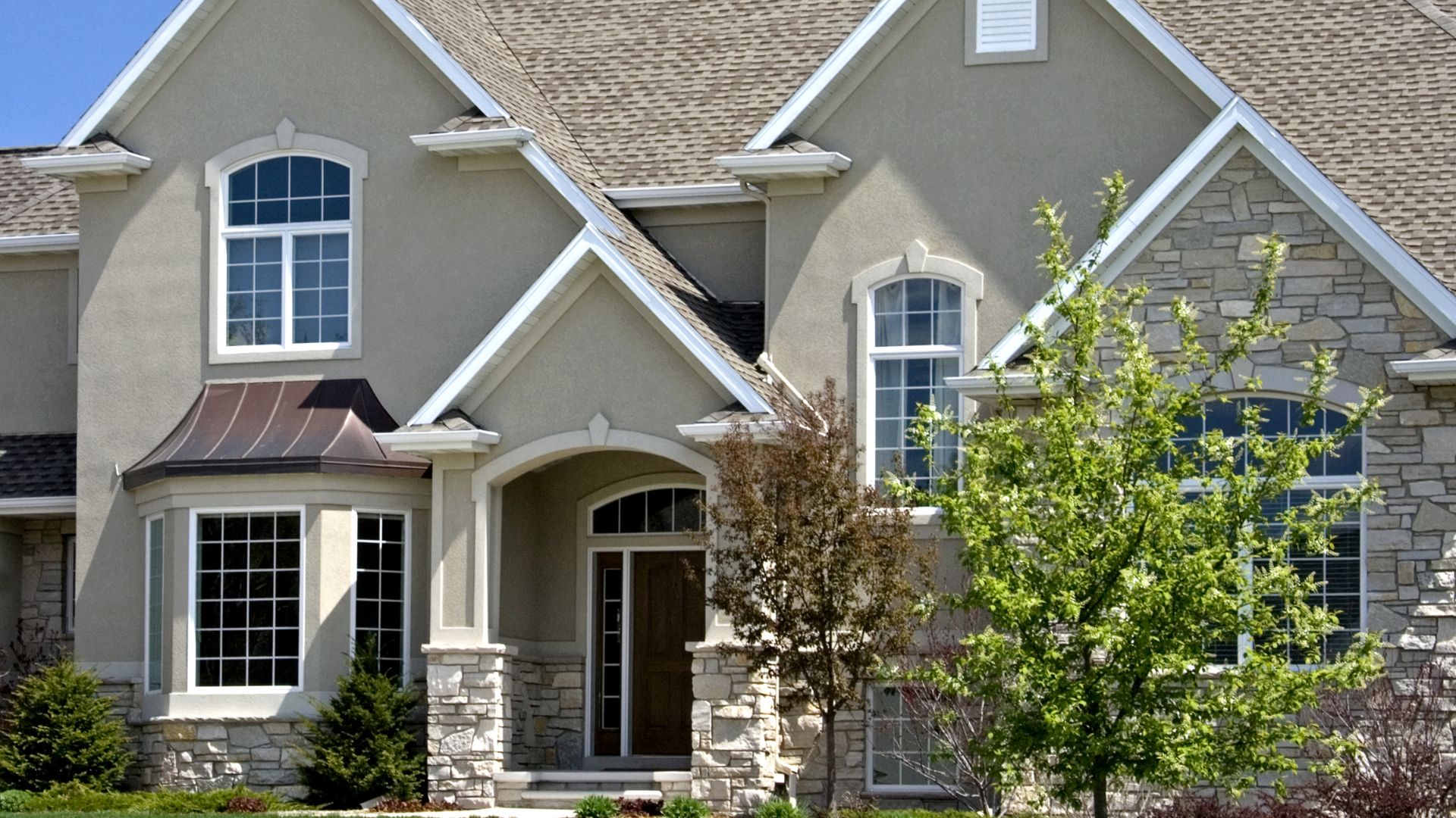 Large suburban two-story house with stone and stucco exterior and arched windows
