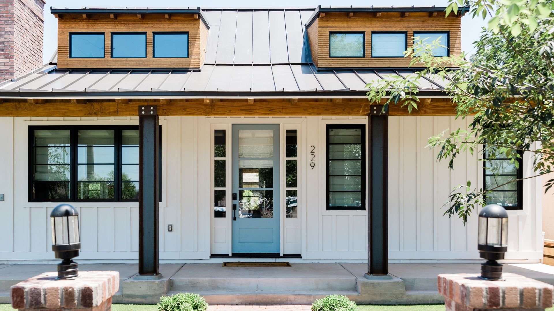 Modern farmhouse with white siding, blue door, and metal roof